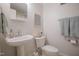 A well-lit powder room featuring a pedestal sink, modern fixtures, and a decorative wall mirror at 1714 Carson St, Raleigh, NC 27608