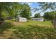 Expansive backyard featuring green grass, mature trees, a storage shed, and a fenced perimeter at 1734 Stage Rd, Durham, NC 27703