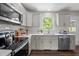 Well-lit kitchen featuring stainless steel appliances, white cabinets, and a view of the lush greenery outside the window at 1734 Stage Rd, Durham, NC 27703
