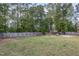 Large backyard with a wooden fence, mature trees, playground equipment, and a grassy area at 180 Long Grass Dr, Smithfield, NC 27577