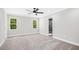 Spacious bedroom featuring two windows for natural light, carpet flooring, ceiling fan, and ensuite bathroom at 185 Millwood Dr, Clayton, NC 27527