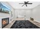 Cozy living room with fireplace, ceiling fan, and windows to view the outdoors at 185 Millwood Dr, Clayton, NC 27527
