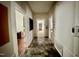 A hallway with white walls, and tile flooring, leading to several rooms, including a bathroom in the distance at 211 Webb St, Roxboro, NC 27573