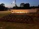 Illuminated Smith Farm community sign with manicured flower beds at dusk at 2919 Winter Crop Way, Apex, NC 27502