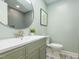 Bathroom with unique tile flooring, patterned wallpaper, and vanity with round mirror at 3009 Hillmer Dr, Raleigh, NC 27609