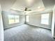 A large bedroom with multiple windows, tray ceiling, and a ceiling fan at 327 Bishop Ln, Sanford, NC 27330