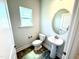 Powder room featuring a pedestal sink, toilet, decorative mirror, and a window providing natural light at 356 Bishop Ln, Sanford, NC 27330