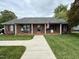 Charming brick home with a covered front porch, tidy landscaping, and an American flag at 3605 Mine Creek Rd, Burlington, NC 27217