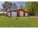 Exterior view of a vibrant red barn with multiple garage doors, situated on a lush green lawn at 435 Salt And Light Ln, Henderson, NC 27537