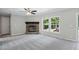 Spacious living room featuring a stone fireplace, ceiling fan, carpet, and a large windows at 4467 Virgilina Rd, Roxboro, NC 27574