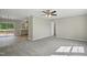 Bright living room featuring plush carpeting, a ceiling fan, and a view into the kitchen and outdoor deck at 4467 Virgilina Rd, Roxboro, NC 27574