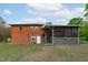 Backyard view of a brick home featuring a screened-in porch and ample lawn space at 5144 Jeffries St, Raleigh, NC 27606