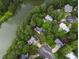 An aerial view shows homes nestled among lush trees along a serene lake at 6 Chelan Ct, Durham, NC 27713