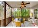 Screened porch with table, chairs, and ceiling fan, offering serene views of the surrounding trees at 6 Chelan Ct, Durham, NC 27713