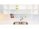 A modern kitchen sink featuring quartz countertops with decoratively styled display shelving and stainless steel hardware and fixtures at 6715 Princeton Kenly Rd, Princeton, NC 27569