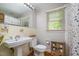 Functional bathroom featuring a pedestal sink, toilet, and shower with a decorative curtain at 708 W Main St, Carrboro, NC 27510