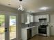 Open kitchen with stainless steel appliances, modern pendant lights, and access to the deck at 717 Papsworth Ct, Fuquay Varina, NC 27526