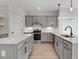 A modern kitchen with grey cabinets, marble countertops, a kitchen island, and stainless steel appliances at 72 Glenwood Pl, Kenly, NC 27542