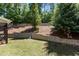 Landscaped backyard with retaining wall, lush green grass, and wooded backdrop for a serene outdoor space at 8840 Forester Ln, Apex, NC 27539