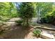 Secluded backyard with mature trees, a wooden fence, and garden beds at 8840 Forester Ln, Apex, NC 27539