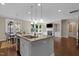 Open kitchen featuring island, stainless steel appliances, and hardwood floors connecting to the living area at 8840 Forester Ln, Apex, NC 27539