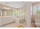 Bright bathroom with double sinks, white cabinetry, a soaking tub, and a separate glass-enclosed shower at 10320 Crisp Dr, Raleigh, NC 27614