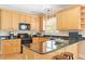 Kitchen with wooden cabinetry, black countertops, an island with stools, and stainless steel appliances at 10320 Crisp Dr, Raleigh, NC 27614