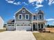 Charming two-story home featuring gray siding, white trim, and a spacious three-car garage and well manicured lawn at 105 S Mule Way # 89, Benson, NC 27504