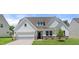 Charming home with a white exterior, well-manicured lawn, a two-car garage and stone accents at 1306 Cricket St, Elon, NC 27244