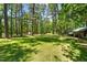 View of a spacious backyard with lush green grass surrounded by mature trees and outbuildings at 1414 Walter Bright Rd, Sanford, NC 27330