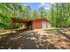 Exterior of the red outbuilding featuring two garage doors and an attached covered area at 1414 Walter Bright Rd, Sanford, NC 27330
