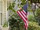 A welcoming home exterior adorned with lush greenery and an American flag at 1712 Briarforest Pl, Raleigh, NC 27615
