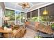 This bright sunroom features screened windows, wicker furniture, ceiling fan, and patterned rug at 1712 Briarforest Pl, Raleigh, NC 27615