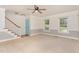 Bright living room with carpet, ceiling fan, stairs, and turquoise door at 200 Weybossett Rd, Henderson, NC 27537