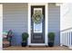 Elegant front door adorned with a wreath, flanked by potted plants, offering a warm welcome at 201 Annabelle Blue Drive, Wake Forest, NC 27587