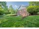 Expansive backyard featuring lush greenery, a brick retaining wall and a shed at 2457 Millbrook Dr, Haw River, NC 27258