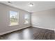 Bright bedroom with dark, wide plank flooring, neutral paint, and large windows providing plenty of natural light at 2650 Turner Pines Dr, New Hill, NC 27562