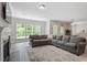 Bright living room with a gray sectional sofa, fireplace, and views of the backyard at 2650 Turner Pines Dr, New Hill, NC 27562