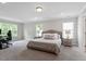 Spacious main bedroom with plush carpeting, neutral paint, recessed lighting, and large windows showcasing greenery at 2650 Turner Pines Dr, New Hill, NC 27562