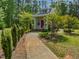 Cottage-style home with a red door, columned front porch, and surrounded by lush landscaping at 280 Dreamcatcher Trl, Youngsville, NC 27596