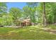 Lush green backyard with mature trees, connected carport, sunroom and green lawns at 300 Wakewood Ct, Raleigh, NC 27615