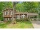 Split level home with brown siding, covered parking, and a charming front porch with flowering shrubbery at 300 Wakewood Ct, Raleigh, NC 27615