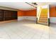 This basement with stairs, shelves, white floors, and orange walls is waiting for your ideas at 3209 Marie Dr, Raleigh, NC 27604