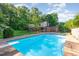 An inviting pool with a diving board surrounded by a stone deck and lush greenery at 3209 Marie Dr, Raleigh, NC 27604
