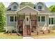 Inviting two-story home with a covered front porch, wood stairs, landscaping, and a white front door at 35 Fire Tower Dr, Rougemont, NC 27572