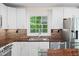 Close-up of kitchen with white cabinets, stainless appliances, natural wood countertops and a beautiful view of mature trees at 35 Fire Tower Dr, Rougemont, NC 27572