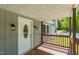 Charming covered porch with a white door, exterior lighting, and wood railings, creating a welcoming entrance at 35 Fire Tower Dr, Rougemont, NC 27572