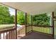 Spacious covered porch with wood flooring and railings, offering beautiful views of the surrounding greenery at 35 Fire Tower Dr, Rougemont, NC 27572