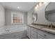 Bathroom showcasing a soaking tub, granite vanity with double sinks, and a bright window at 4589 Freedom Dr, Burlington, NC 27215