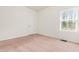 Clean bedroom with neutral walls, plush carpet, a window with blinds, and a door at 525 Durants Neck Ln, Morrisville, NC 27560
